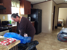 Deborah Rassi, 59, cleans her new kitchen. She's holding a bag of donated clothing, one of many that volunteers left in the new mobile home. Deborah Rassi, 59, cleans her new kitchen. She's holding a bag of donated clothing, one of many that volunteers left in the new mobile home.