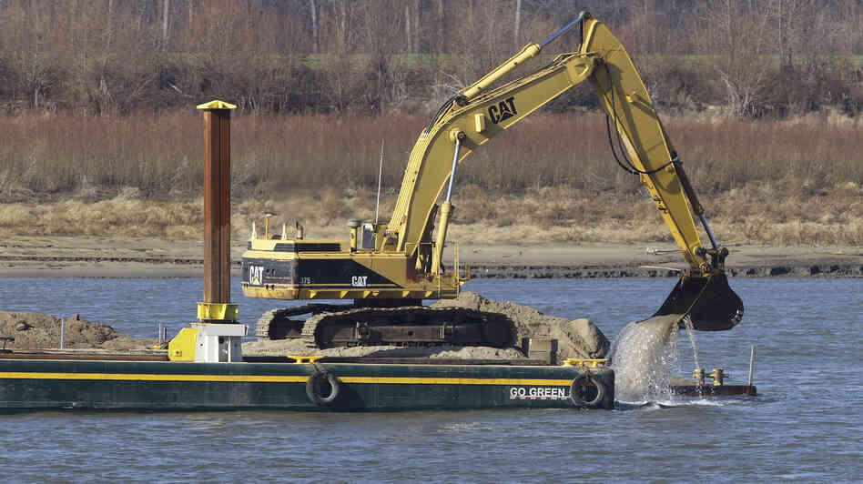 An excavator perched on a barge removes rocks from the Mississippi River in Thebes Ill.