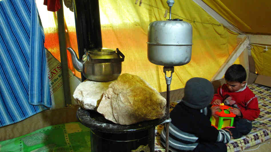 Oula's sons play in her family's tent at the al-Marj refugee camp in Lebanon's Bekaa Valley. A small gas stove in the center of the tent keeps the family warm and boils water for tea.