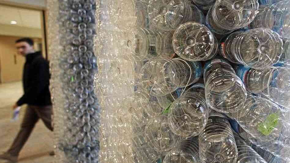 A student walks past a sculpture made of empty water bottles on the University of Vermont campus. UVM has banned the sale of bottled water.