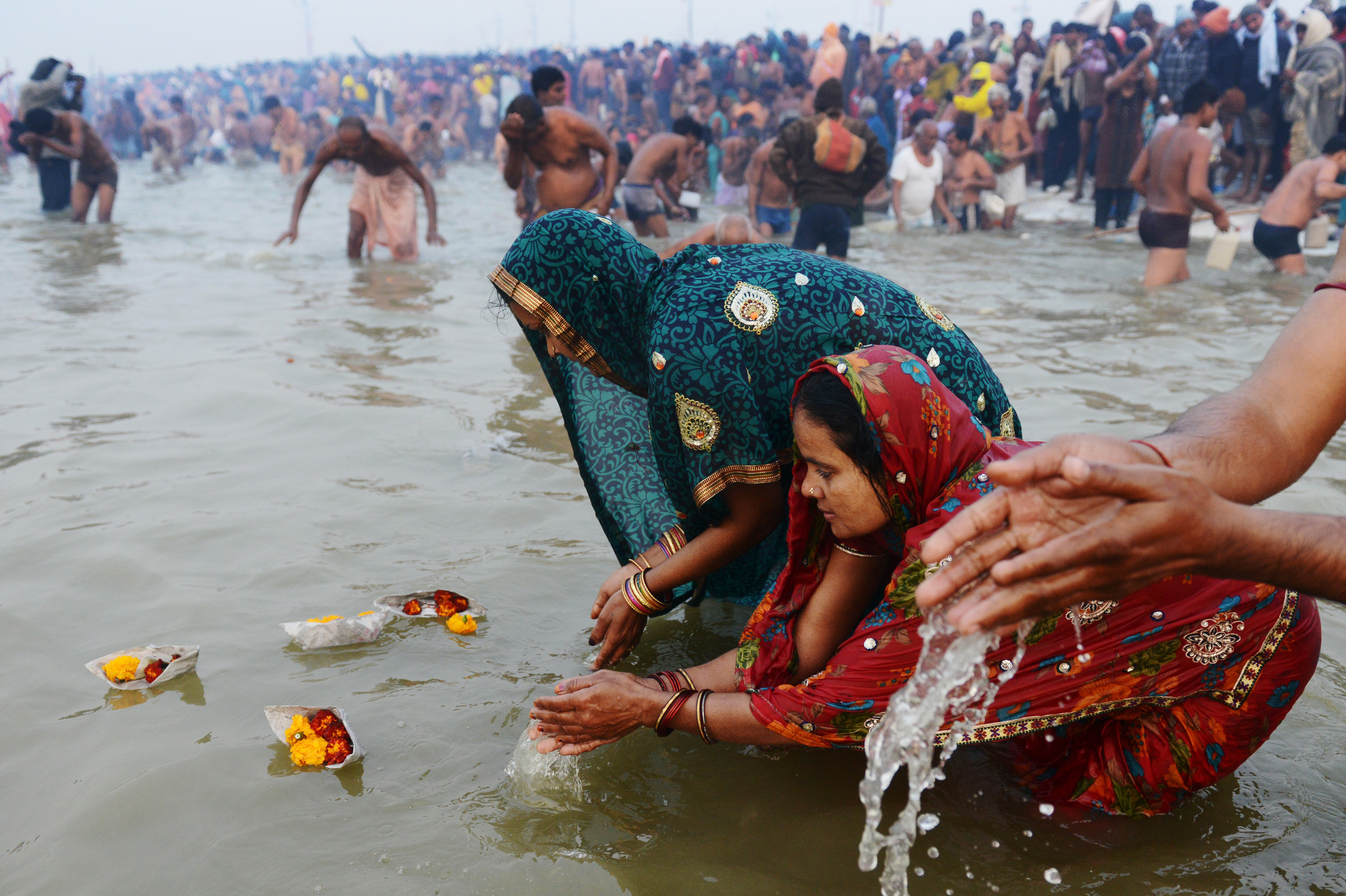 Pilgrims release offerings in the river's current while bathing.