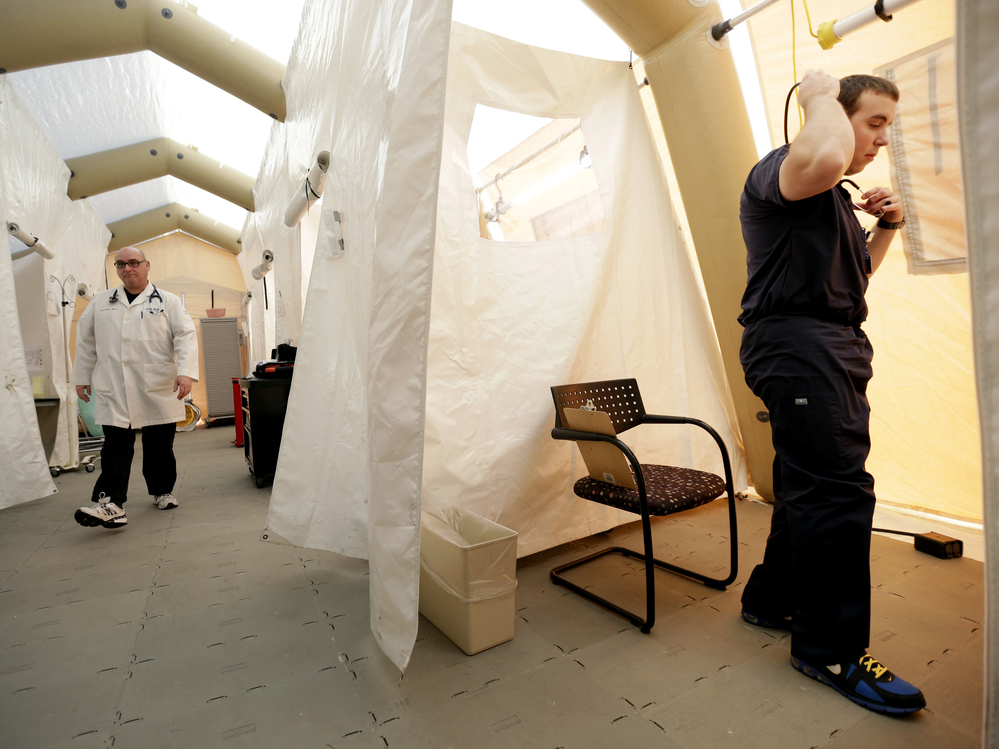 Physician assistants Scott Fillman (left) and Andrew Hunadi get ready to see patients with flu symptoms, in a tent erected just outside the emergency entrance at the Lehigh Valley Hospital in Allentown, Pa.