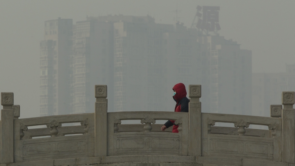 A man wearing a mask walks on a stone bridge in a park on a hazy day in Beijing on Monday. Beijing schools kept children indoors and hospitals saw a spike in respiratory cases following a weekend of off-the-charts pollution in China's smoggy capital, the worst since the government began being more open about air-quality data.