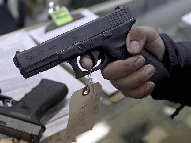 At a gun shop in Phoenix, a  customer holds a handgun. Among the executive actions President Obama is expected to propose is an expansion of background checks for gun buyers.