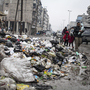 A family crosses a street piled with rubbish in Aleppo, Syria, on Jan. 5.