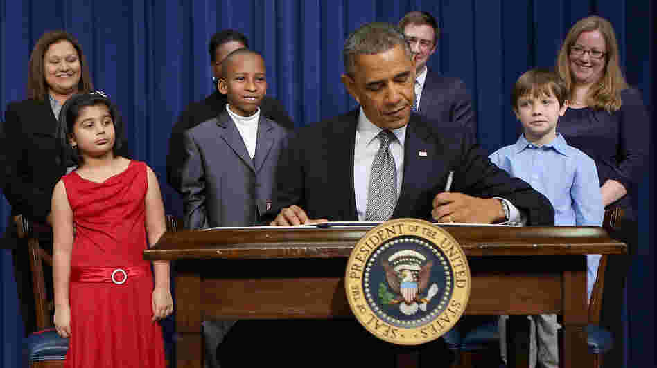 President Obama signs a series of executive orders Wednesday about the administration's gun law proposals as Vice President Biden and children who wrote letters to the White House about gun violence look on.