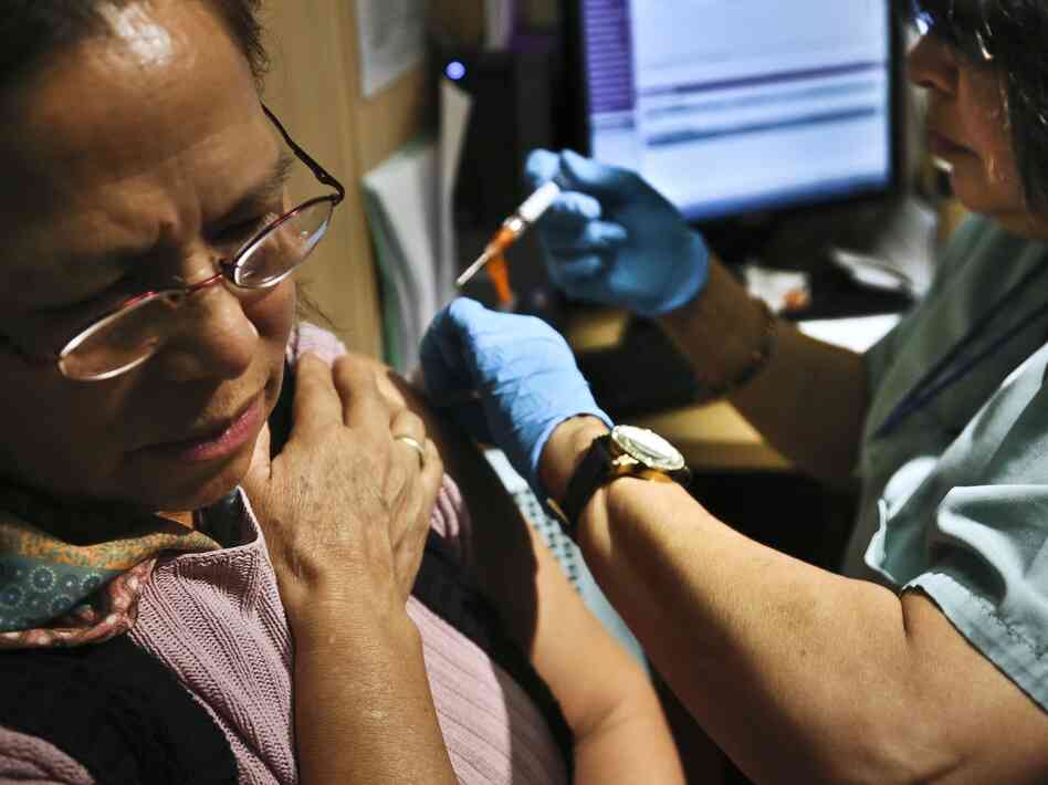 Sonia Despiar, right, a nurse with Gouverneur Healthcare Services, injects Imelda Silva with flu vaccine on Friday, Jan. 11, 2013, in New York. At least 10 elderly people and two children in New York have died from the flu and hospitalizations are climbing as the illness hits every county in the state.