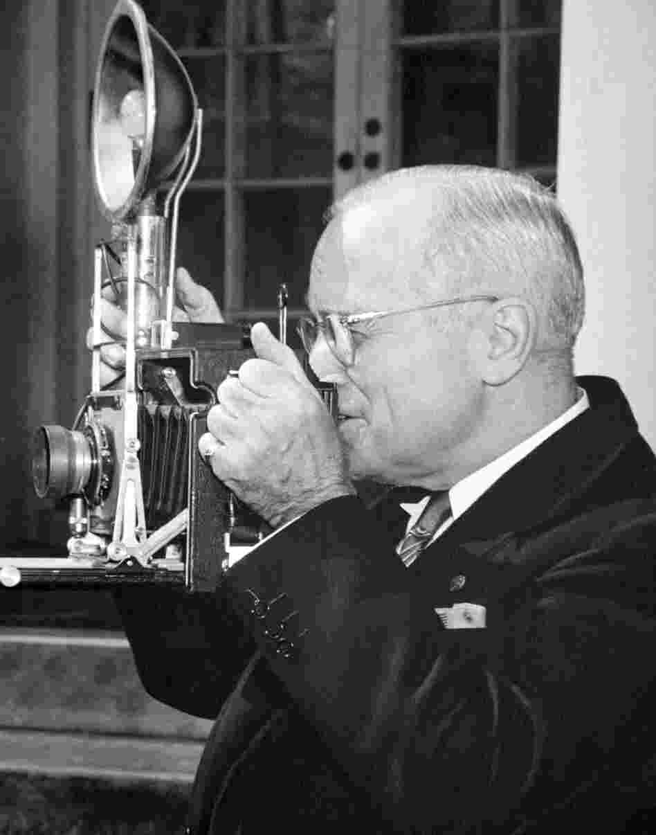 President Harry S. Truman tries out a speed graphic camera given to him by members of the WHNPA during a meeting at the White House Rose Garden, 1948.