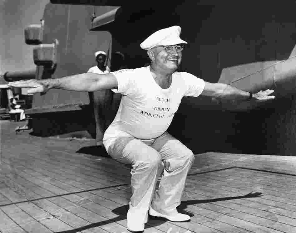 President Truman, wearing a shirt that reads "Coach Truman, Athletic Department," leads exercises on the deck of the USS Missouri on his return trip to Washington from Brazil, 1947.