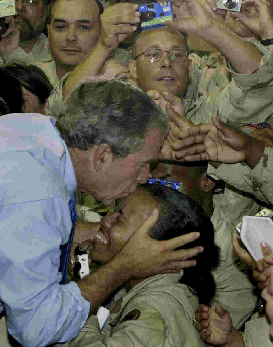 President George W. Bush kisses a soldier as he greets U.S. military personnel at As-Sayliyah base near Doha, Qatar, 2003.
