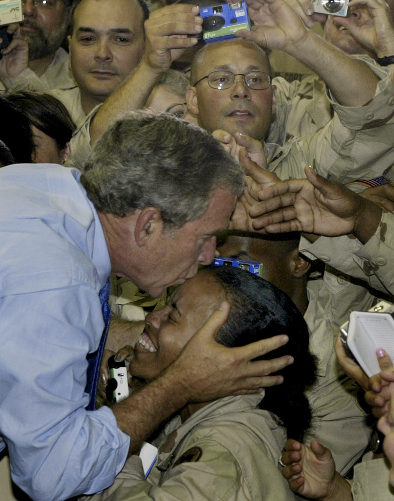 President George W. Bush kisses a soldier as he greets U.S. military personnel at As-Sayliyah base near Doha, Qatar, 2003.