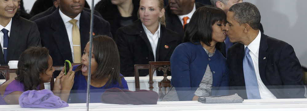 President Barack Obama kisses first lady Michelle Obama as their daughters Sasha, left, and Malia, second from left, look on during the Inaugural parade.