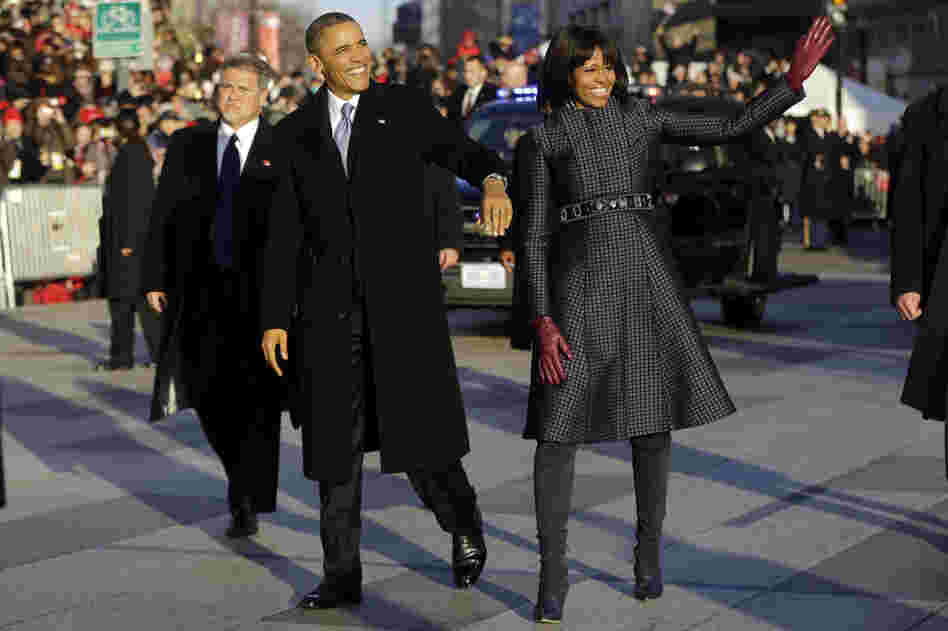 Obama and Michelle walk in the inauguration parade near the White House. The first lady chose a coat by designer Thom Browne.