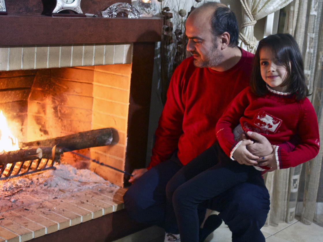 Sotiris Sotiriou, 41, and his daughter Sophia, 5, check out the olive-wood kindling in the fireplace that heats their family's home.
