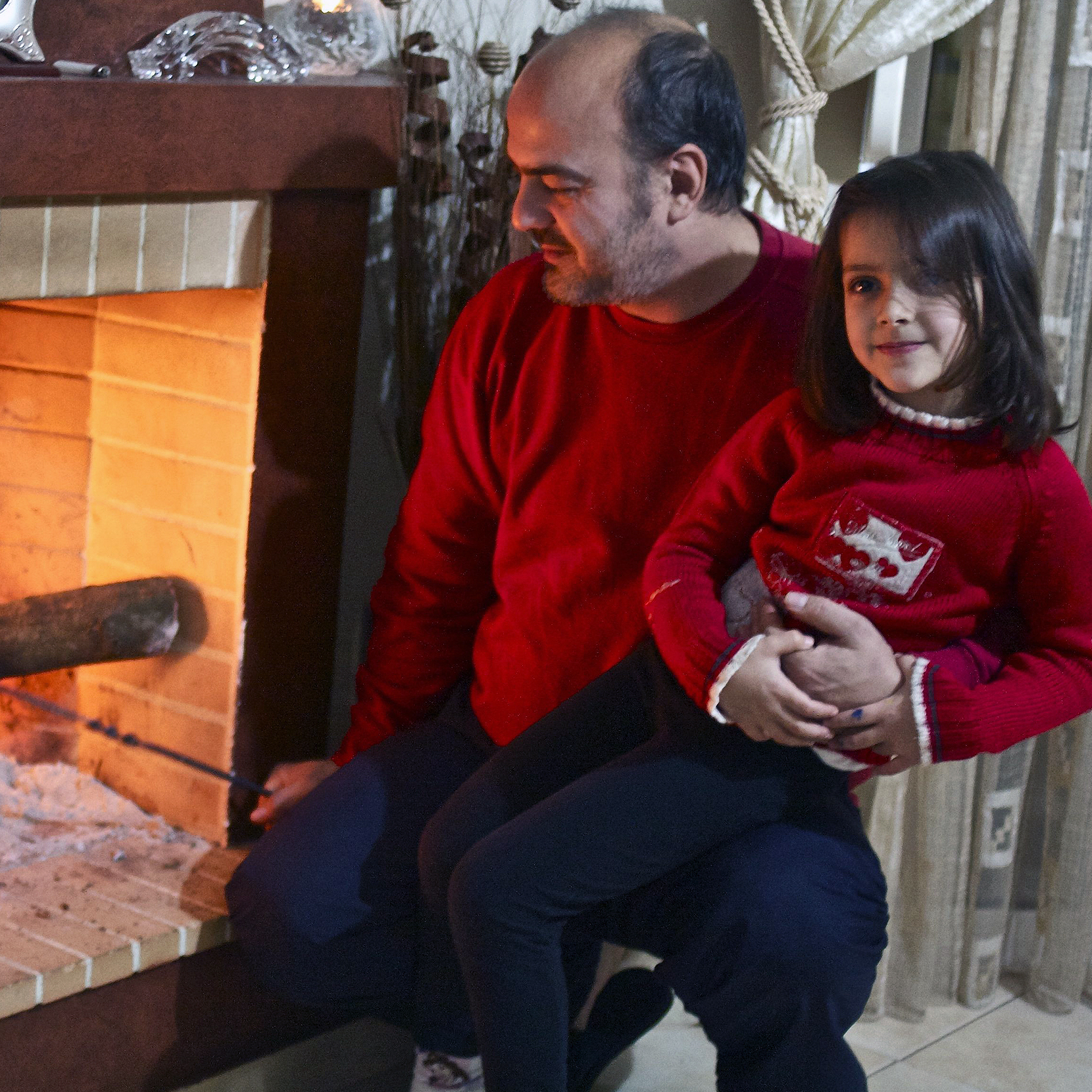 Sotiris Sotiriou, 41, and his daughter Sophia, 5, check out the olive-wood kindling in the fireplace that heats their family's home.