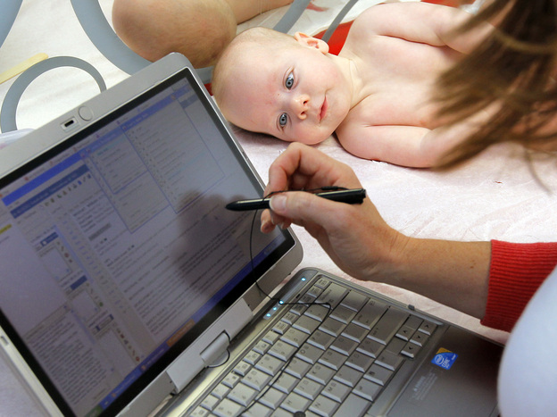 Patient William Wishart, age 4 months, looks on as Dr. Melanie Walker uses a portable computer to enter information from his exam into an electronic medical records system, in North Raleigh, N.C., in November.