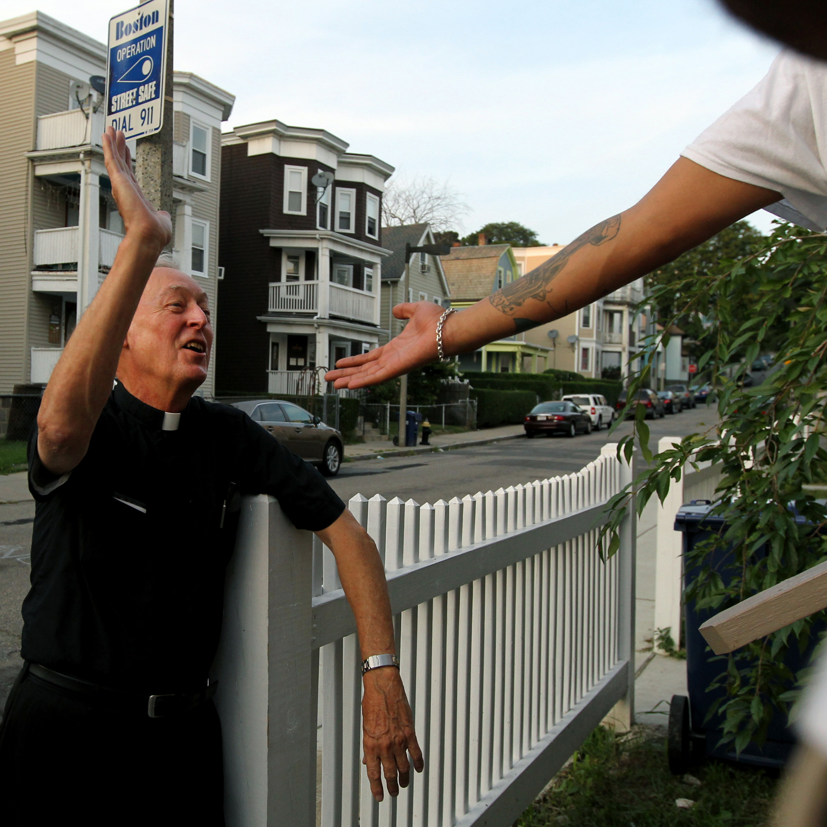 Father Richard "Doc" Conway, of St. Peter Church, high-fives a man while walking the neighborhood on a Friday night.