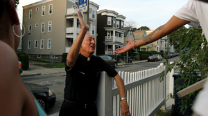 Father Richard "Doc" Conway, of St. Peter Church, high-fives a man while walking the neighborhood on a Friday night.