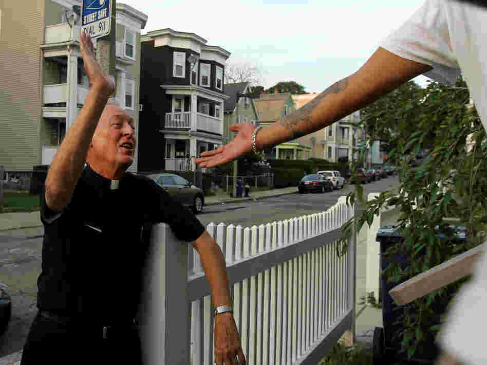 Father Richard "Doc" Conway, of St. Peter Church, high-fives a man while walking the neighborhood on a Friday night.