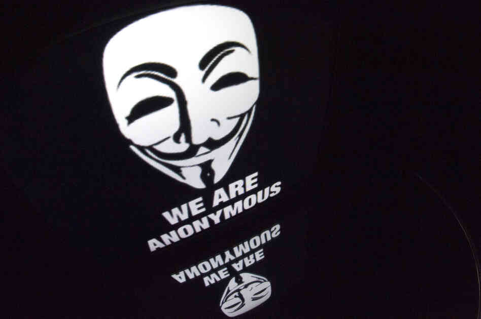 The "Anonymous" logo is seen on a tablet screen. The "Anonymous" logo is seen on a tablet screen.