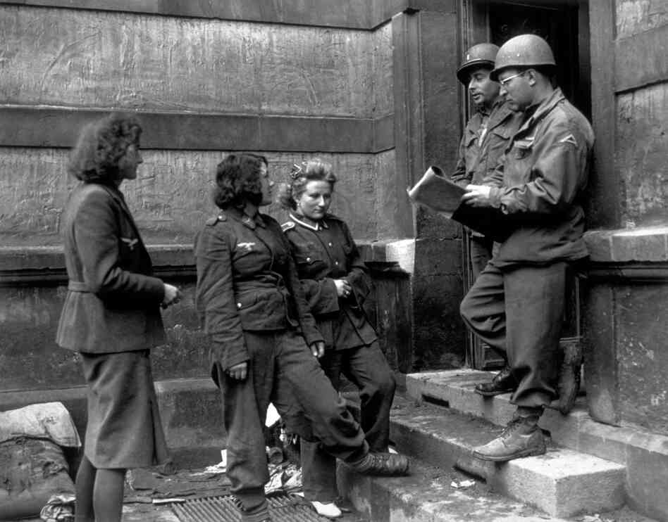 Female German army prisoners being checked in by German-speaking Americans at a German Women's Detention Building in 1945. The women were captured at the front on the 7th U.S. Army sector.