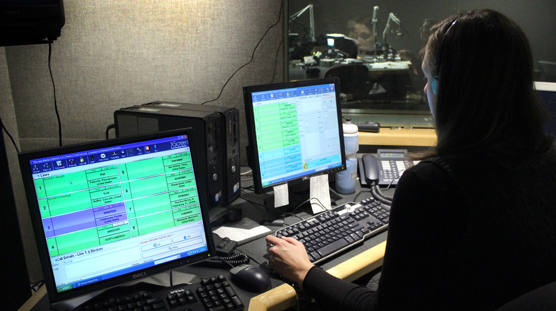 NPR Editorial Assistant Laura Lee takes and screens calls during a live broadcast of Talk of the Nation. Look just above Lee's head to see Neal Conan in the hosting chair on the other side of the glass.