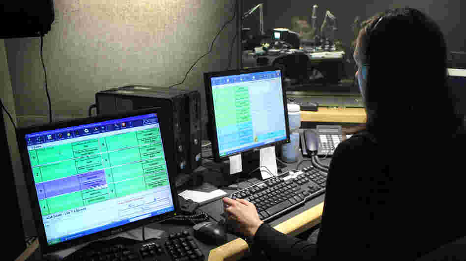 NPR Editorial Assistant Laura Lee takes and screens calls during a live broadcast of Talk of the Nation. Look just above Lee's head to see Neal Conan in the hosting chair on the other side of the glass.