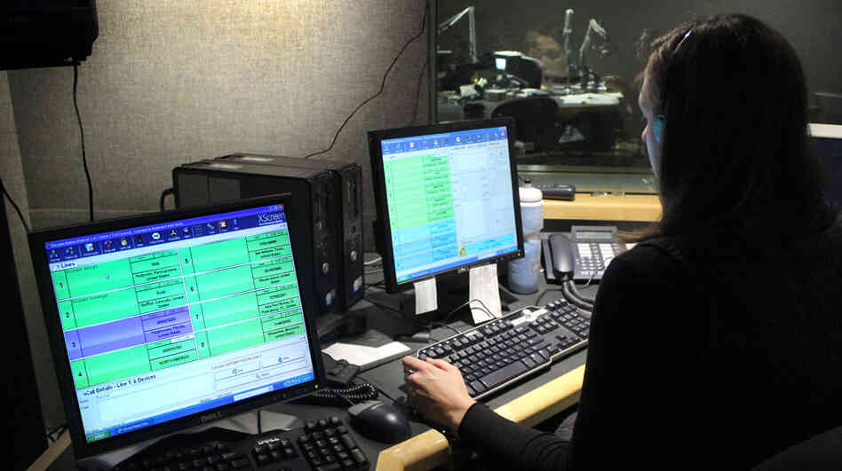 NPR Editorial Assistant Laura Lee takes and screens calls during a live broadcast of Talk of the Nation. Look just above Lee's head to see Neal Conan in the hosting chair on the other side of the glass.