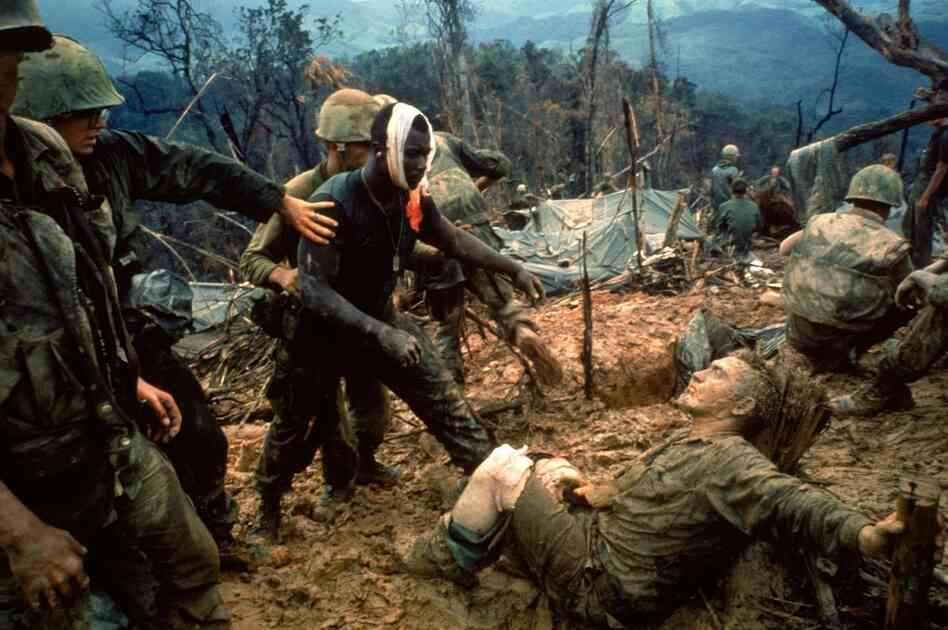 Wounded Marine Gunnery Sgt. Jeremiah Purdie (center, with bandaged head) reaches toward a stricken comrade after a fierce firefight south of the Demilitarized Zone in Vietnam, October 1966.