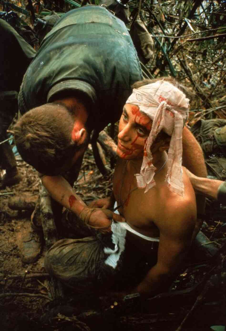 A dazed, wounded American Marine gets bandaged during Operation Prairie near the Demilitarized Zone during the Vietnam War, October 1966.