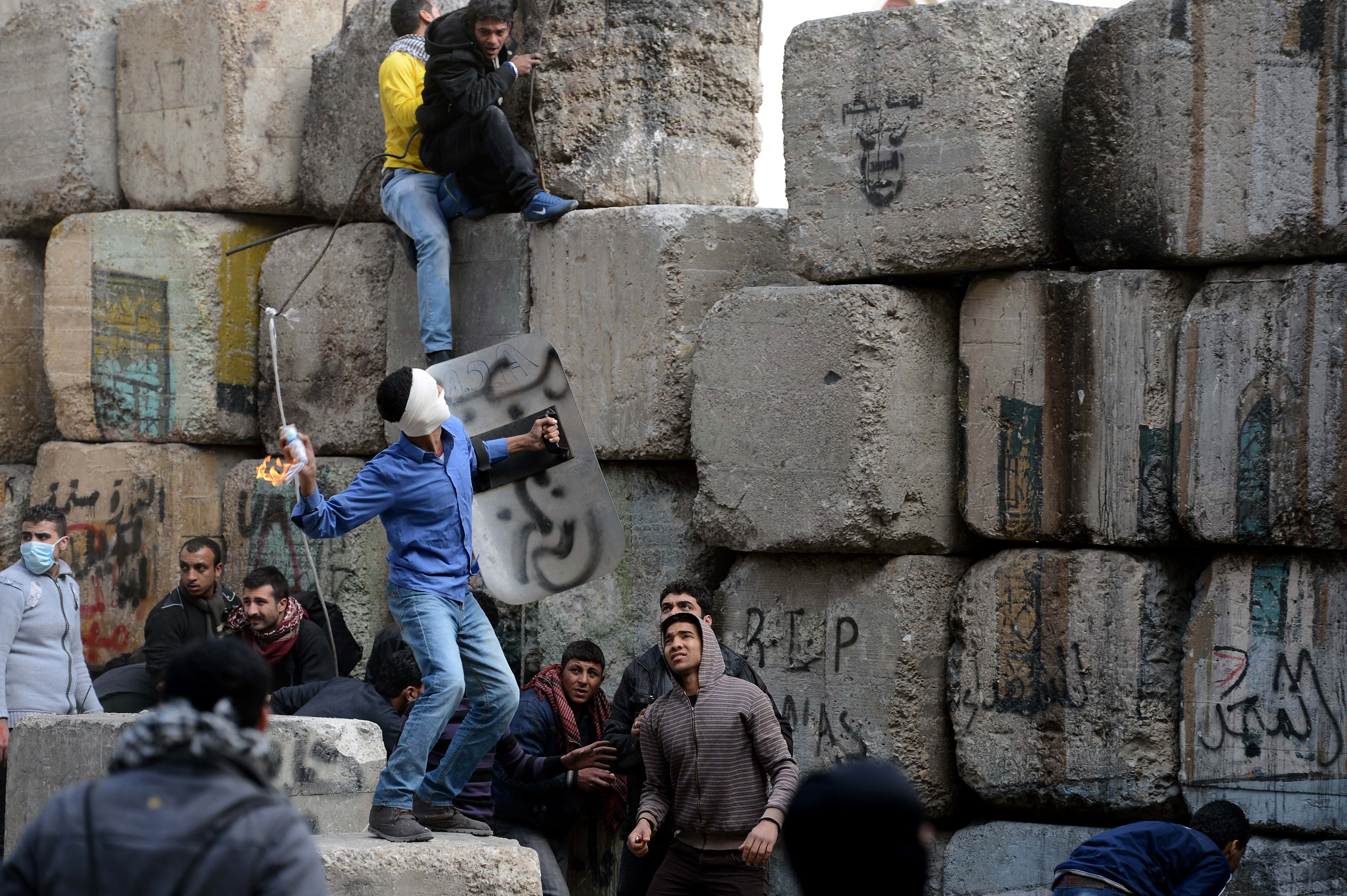 An Egyptian protestor throws a Molotov cocktail towards security personnel in Cairo's Sheikh Rayhan street that leads to the Interior Ministry headquarters, near Tahrir Square, on January 25, 2013. 