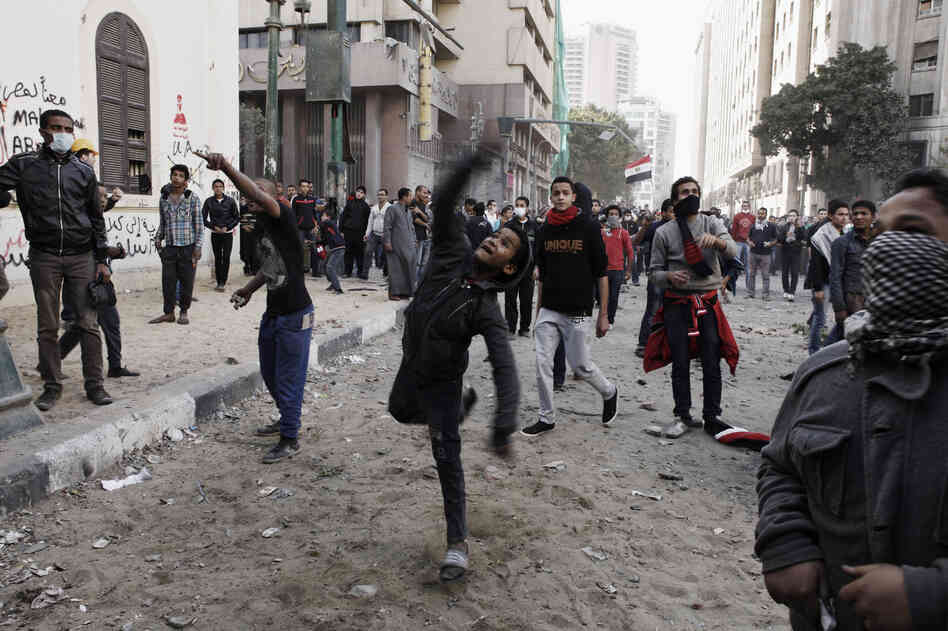 An Egyptian protester throws a rock toward riot police during a demonstration in Tahrir Square on January 25, in Cairo, Egypt.