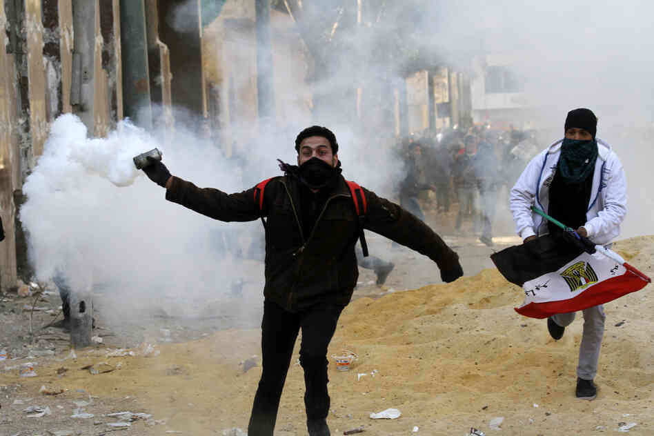 An Egyptian protester runs to throw tear gas during a protest in Tahrir Square on January 25, 2013 in Cairo.