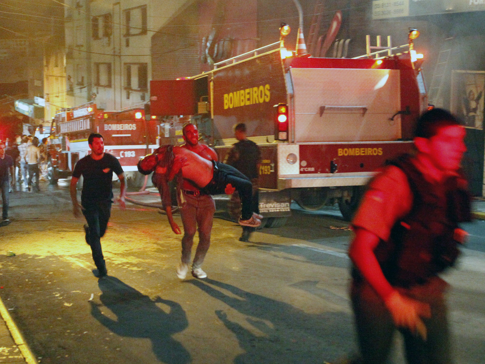 A man carries an injured victim of a fire at the Kiss club in Santa Maria city, Rio Grande do Sul state, Brazil, on Sunday.