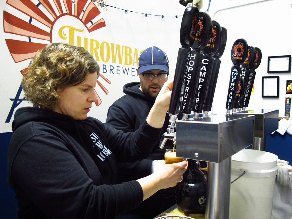 Throwback Brewery co-owner Nicole Carrier and assistant brewer Chris Naro pour beer for customers at their North Hampton, N.H., taproom.