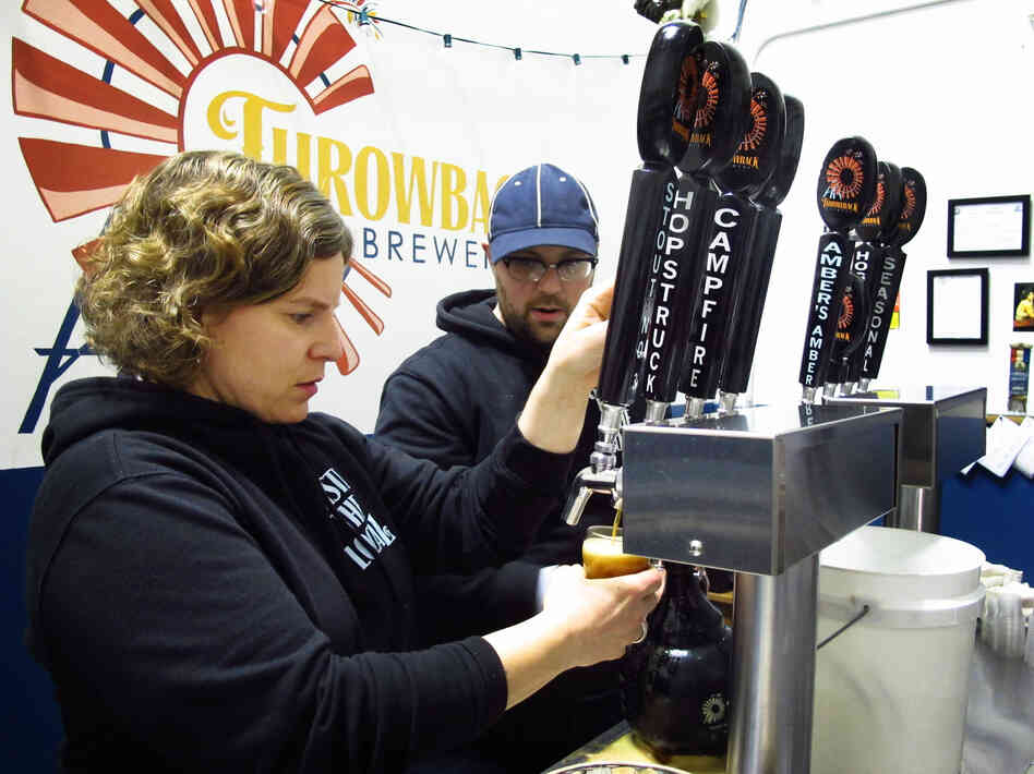 Throwback Brewery co-owner Nicole Carrier and assistant brewer Chris Naro pour beer for customers at their North Hampton, N.H., taproom.