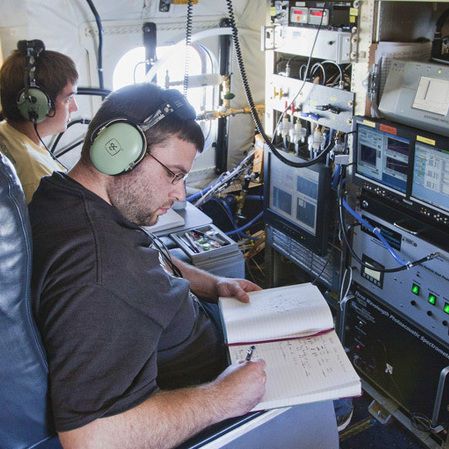 Terry Lathem, a graduate student in Georgia Tech's School of Earth and Atmospheric Sciences, takes notes aboard a NASA DC-8 aircraft gathering samples of microorganisms in the atmosphere.