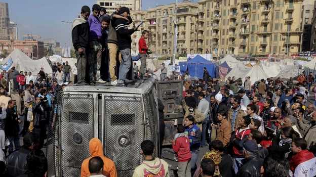 Protesters surround a burned Egyptian army vehicle in Cairo on Jan. 29, 2013. (AP)