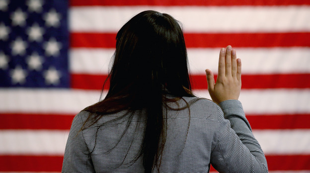 A woman takes the oath of allegiance during a naturalization ceremony at the district office of the U.S. Citizenship and Immigration Services in Newark, N.J.