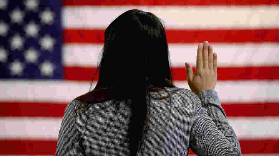 A woman takes the oath of allegiance during a naturalization ceremony at the district office of the U.S. Citizenship and Immigration Services in Newark, N.J.