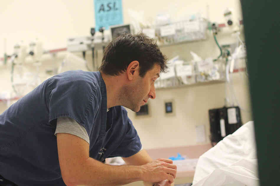 While repairs continue in the basement below, Dr. William Goldberg talks to a hospital patient who reports flu-like symptoms.
