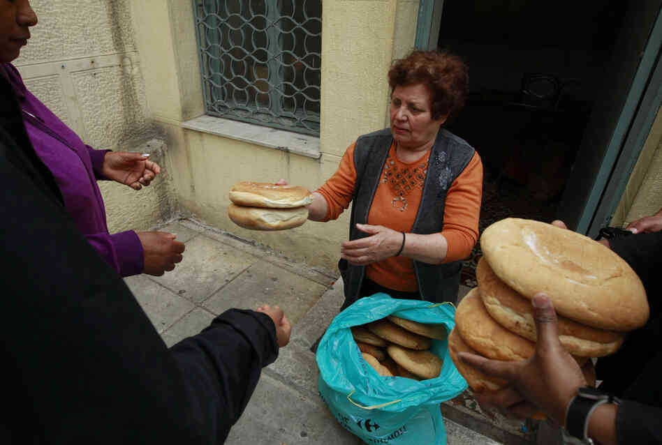 Georgia Kolia, 63, has two adult children, both unemployed. She works as a volunteer distributing loaves of bread at the Agia Zonis Orthodox church soup kitchen for the poor in Athens, Greece, in April 2012.