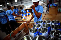 Workers arrange paint buckets before they are filled at a warehouse in the Caracol Industrial Park, which Haiti is billing as the largest in the Caribbean.