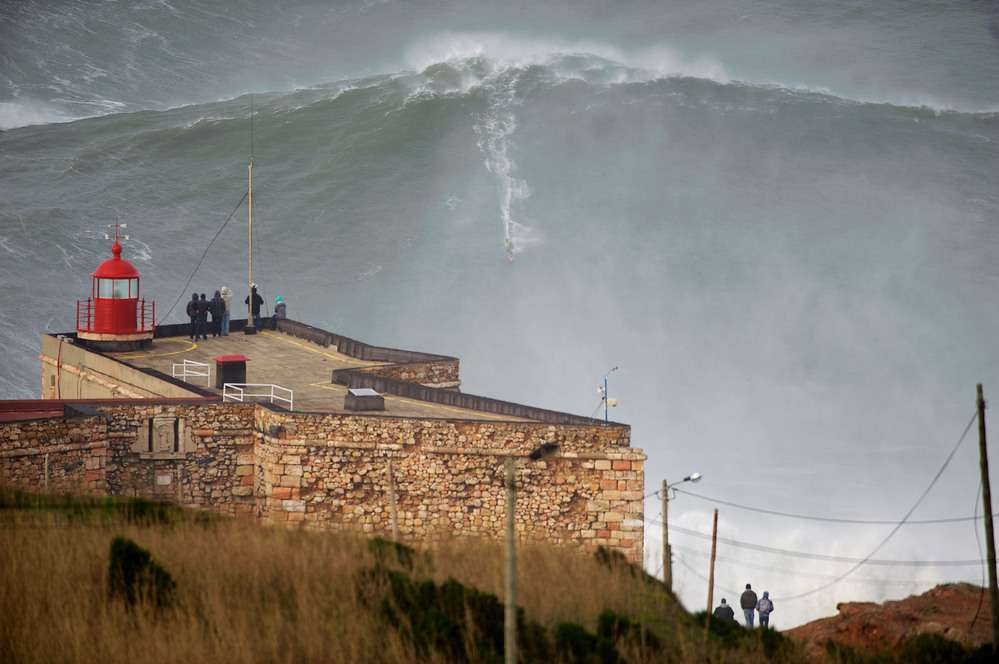 American surfer Garrett "GMAC" McNamara rides what could be, if confirmed, the biggest wave conquered in history as a crowd watches Monday in Nazare, Portugal.