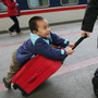 A boy hitches a ride on a suitcase as he waits to board a train at Beijing West Railway Station during Chunyun travel peak on Feb. 8, 2007.