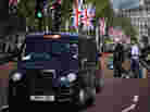 Black taxis drive down The Mall in London. A Chinese company rescued the British automaker that manufactures the famous cabs.