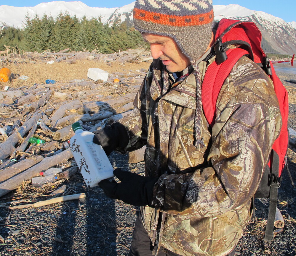 Chris Pallister examines a bottle of what he believes could be a household chemical item on Montague Island.