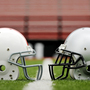 Two football helmets face each other on a field. Two football helmets face each other on a field.