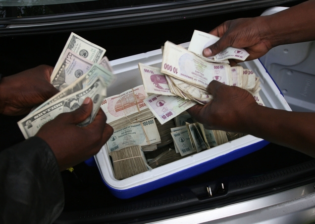 Zimbabwean foreign currency dealers conduct a transaction from the trunk of a car using money stashed in a cooler box in Harare.