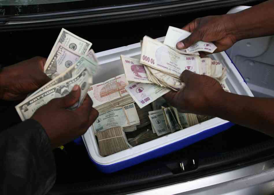 Zimbabwean foreign currency dealers conduct a transaction from the trunk of a car using money stashed in a cooler box in Harare.